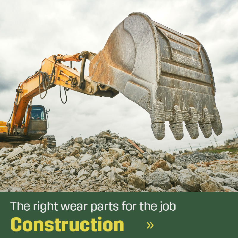 Excavator with bucket operating in a rocky area with the bucket raised above ground. Sagros wear parts for construction are used in machines handling digging and material movement.