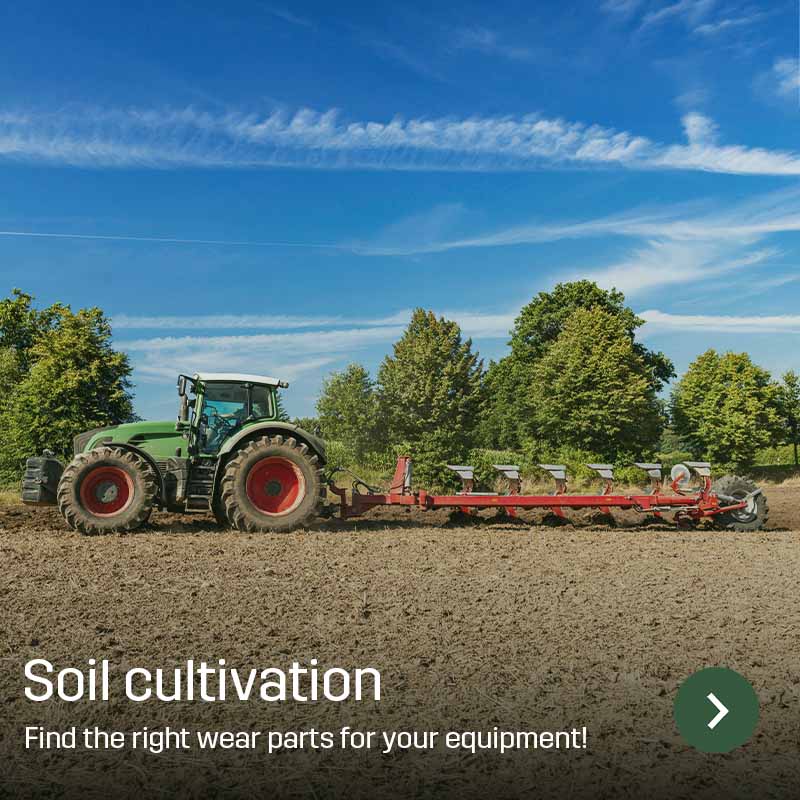 Tractor with plough working in a field, turning soil in long passes with trees in the background. Sagros wear parts are used in tillage equipment for efficient soil preparation before sowing